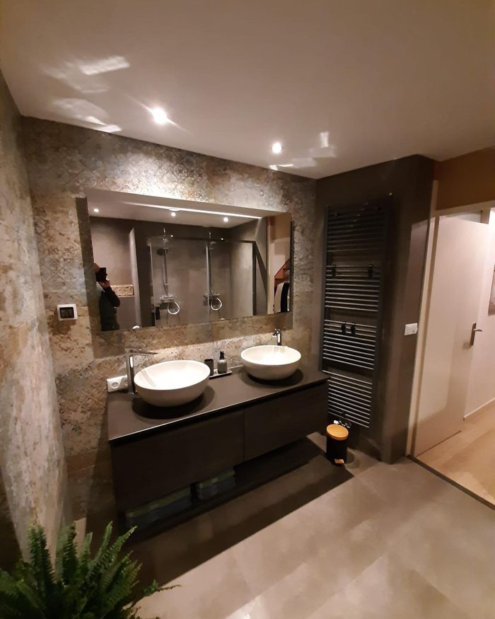 Betonlook badkamer met dubbele wastafel en spiegelwand